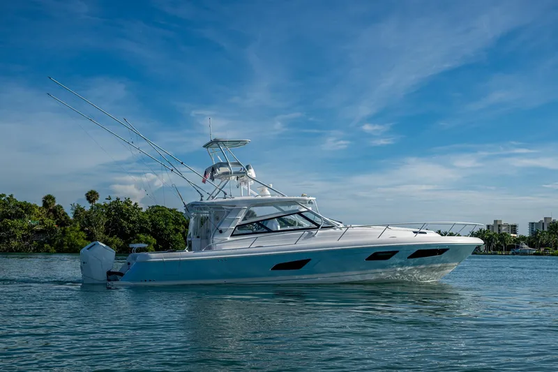 Slide: The Image of 2023 Intrepid 477 Evolution boat cruising on a sunny day, surrounded by lush greenery. - 90