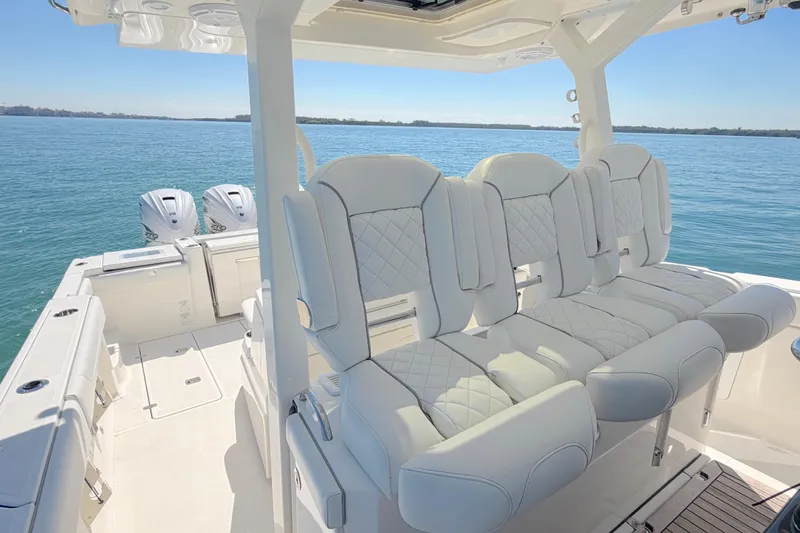 Slide: The Image of 2021 Pursuit S 378 Sport boat interior with luxurious seating and twin engines on a sunny day. - 9