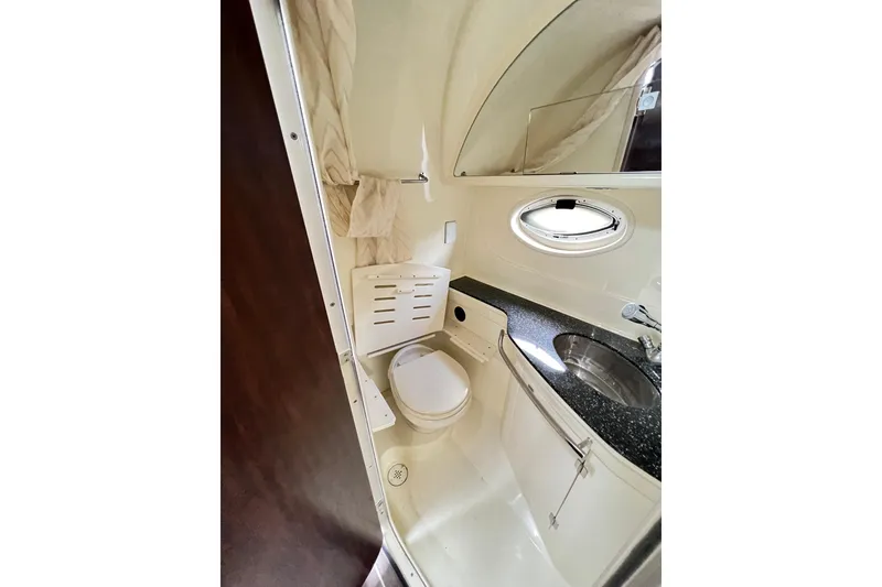 Slide: The Image of 2014 Monterey 320 Sport Yacht bathroom with toilet, sink, and porthole window. - 11