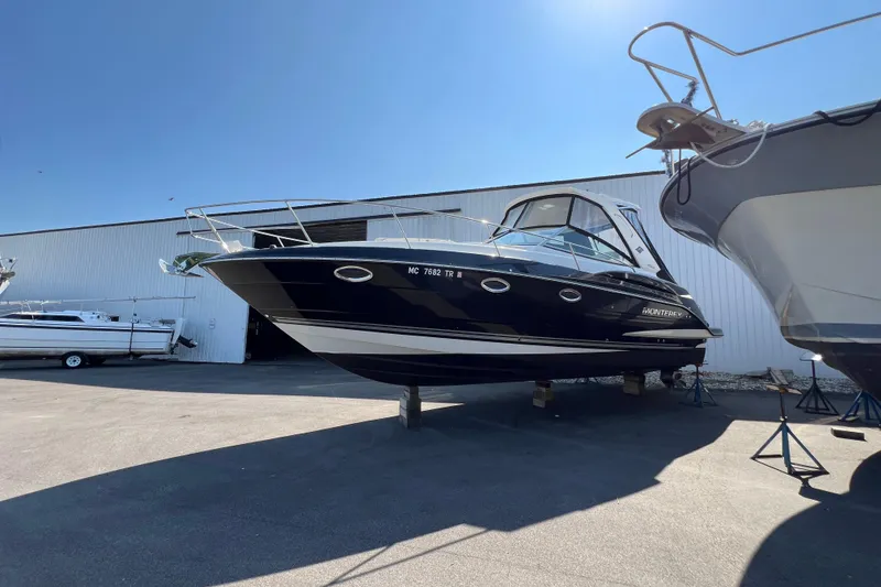Slide: The Image of 2014 Monterey 320 Sport Yacht on dry dock, sleek black design under clear blue sky. - 2