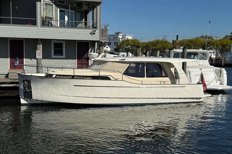 The Image of 2013 Greenline 33 yacht docked at a marina, reflecting sunlight on calm water. - 0