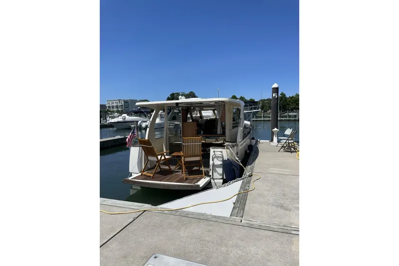 Slide: The Image of 2013 Greenline 33 yacht docked with chairs on deck, clear blue sky. - 19