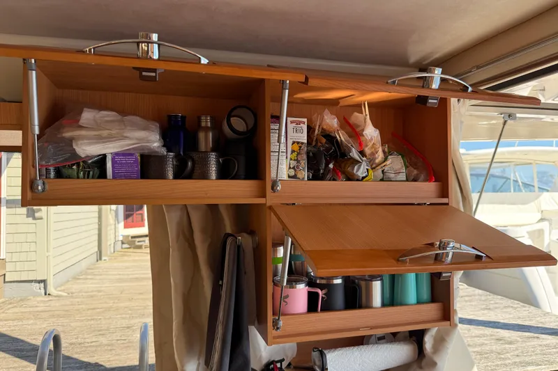 Slide: The Image of Open wooden cabinets in a 2013 Greenline 33 boat, storing kitchen items and snacks. - 36