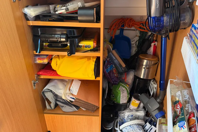 Slide: The Image of Cabinet filled with various household items, including cleaning supplies and kitchen gadgets, on a Greenline 33 boat. - 69