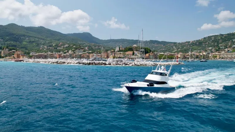 Slide: The Image of 2018 Viking 62 Enclosed Bridge yacht cruising near scenic coastal town. - 5