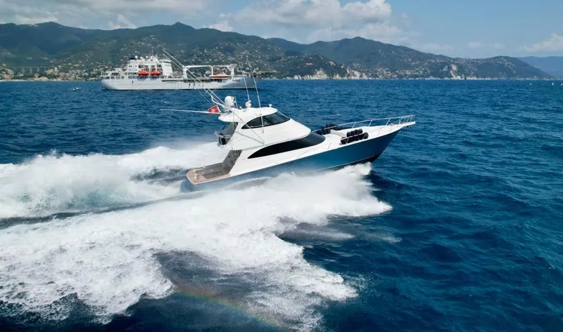 Slide: The Image of 2018 Viking 62 Enclosed Bridge yacht cruising on open sea with scenic coastline. - 8