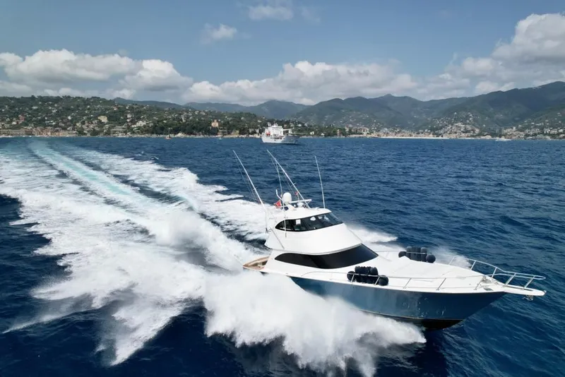 Slide: The Image of 2018 Viking 62 Enclosed Bridge yacht cruising on open sea with scenic coastline backdrop. - 9