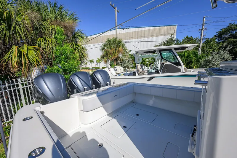 Slide: The Image of 2021 Contender 35 ST boat with triple outboard engines, docked near tropical foliage. - 27