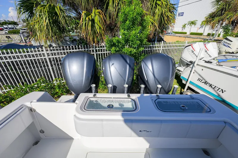 Slide: The Image of 2021 Contender 35 ST boat with triple outboard engines, docked near palm trees. - 35