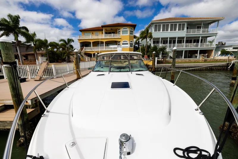 Slide: The Image of 2000 Sea Ray 370 Express Cruiser docked near waterfront homes under a blue sky. - 37