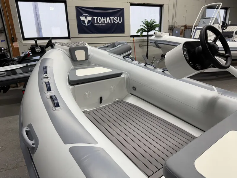 The Image of 2025 Highfield Classic 400 inflatable boat interior with Tohatsu banner in showroom. - 0