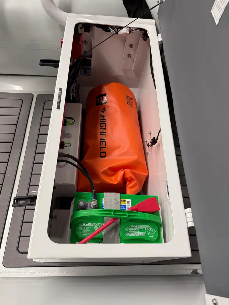 Slide: The Image of Highfield Classic 400 boat storage compartment with battery and orange safety equipment, 2025 model. - 10