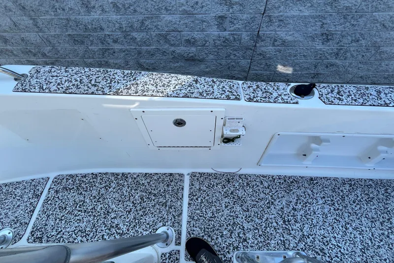 Slide: The Image of 2010 Sea Hunt Triton 220 boat deck with speckled flooring and storage compartments. - 10