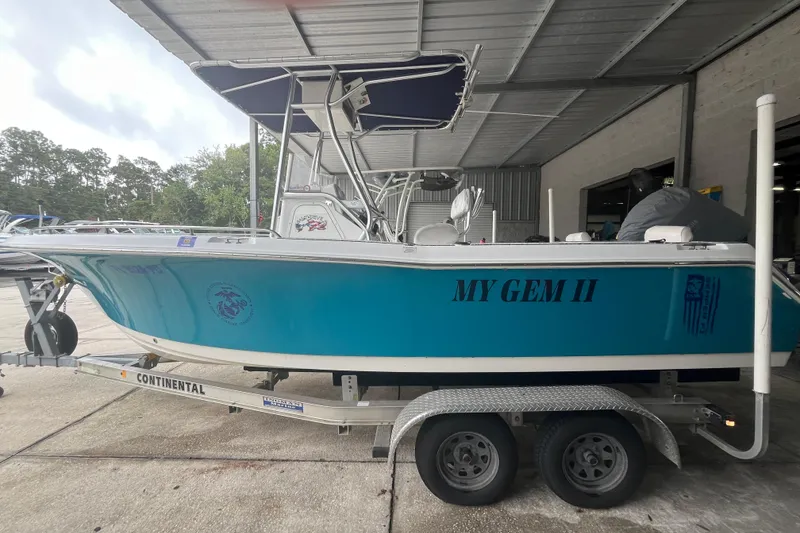 Slide: The Image of 2010 Sea Hunt Triton 220 boat named "My Gem II" on a trailer in a covered area. - 2