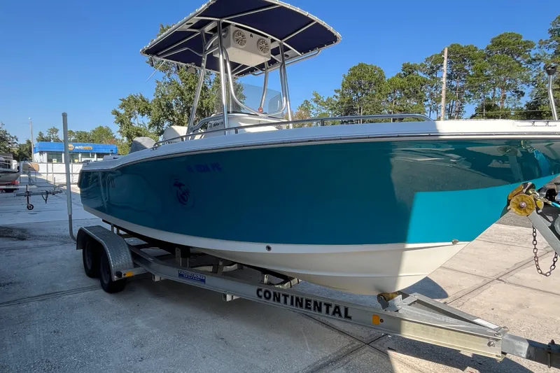 Slide: The Image of 2010 Sea Hunt Triton 220 boat on trailer, blue hull, sunny day, outdoor setting. - 27
