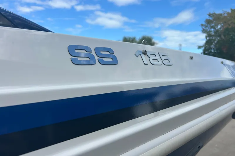 Slide: The Image of 2022 Hurricane SunDeck Sport 185 OB boat with blue stripe under clear sky. - 11
