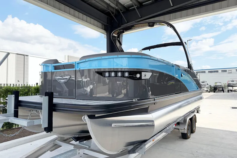 Slide: The Image of 2025 Bennington 23RX pontoon boat on trailer under shelter, showcasing sleek design. - 3