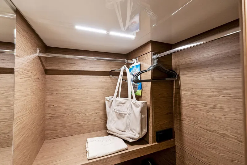 Slide: The Image of Luxurious wooden closet interior on 2020 Ferretti Yachts 920, featuring hangers and a white bag. - 49