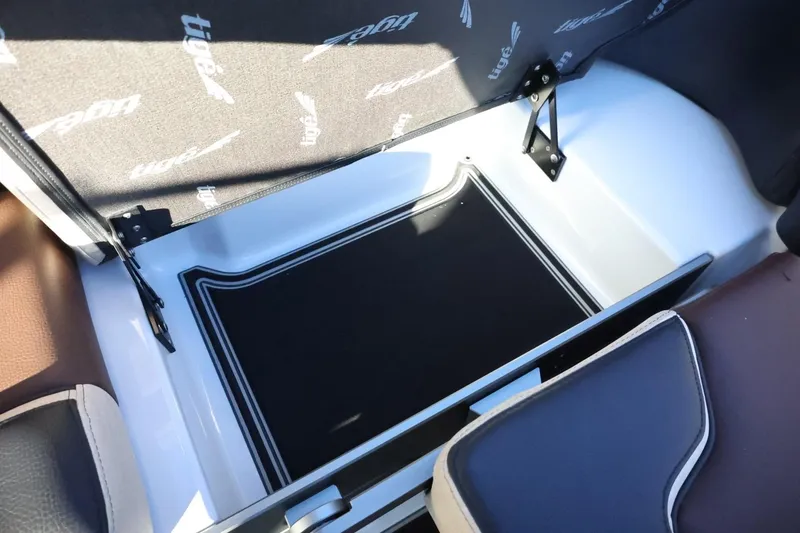 Slide: The Image of 2026 Tigé 24RZX boat storage compartment with cushioned seating and branded upholstery. - 49