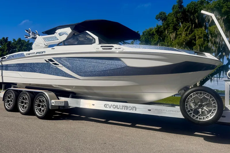 The Image of 2025 Centurion Ri245 boat on trailer, sleek design with metallic accents, parked outdoors. - 9