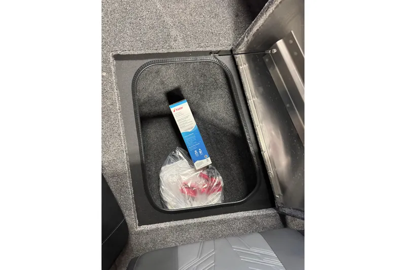 Slide: The Image of Storage compartment in 2026 Tracker Pro Guide V-175 Combo boat, containing a box and plastic-wrapped items. - 18