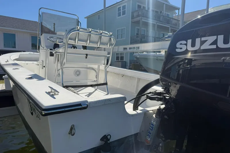 Slide: The Image of 2023 C-Hawk 23 Center Console boat with Suzuki outboard motor, docked near waterfront homes. - 11