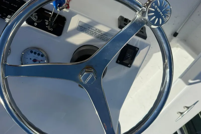 Slide: The Image of Steering wheel of 2023 C-Hawk 23 Center Console boat, featuring chrome finish and dashboard controls. - 16