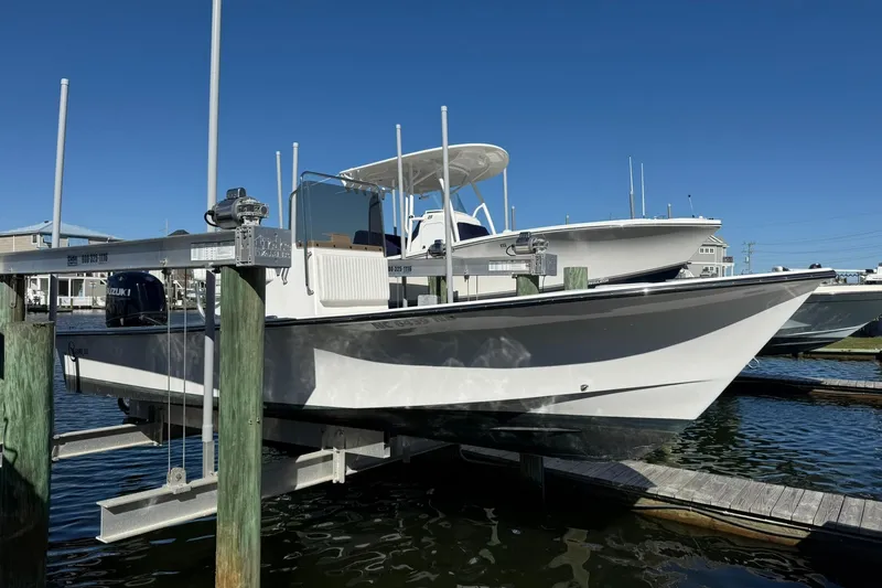 Slide: The Image of 2023 C-Hawk 23 Center Console boat docked on a lift under clear blue skies. - 21