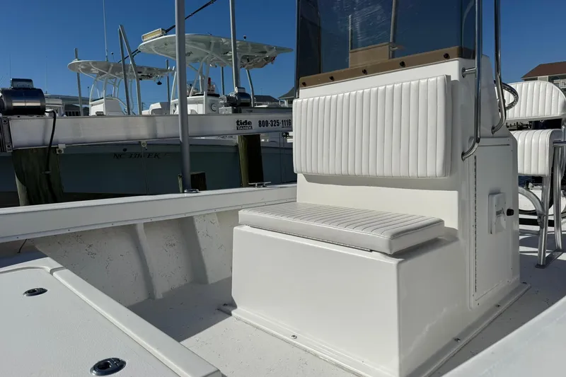 Slide: The Image of 2023 C-Hawk 23 Center Console boat with white seating and console, docked under clear sky. - 4
