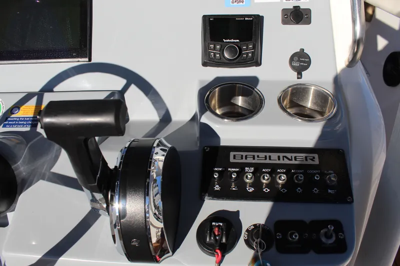 Slide: The Image of 2024 Bayliner CC22 boat dashboard with controls, steering wheel, and cup holders. - 17