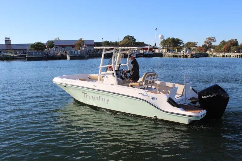 Slide: The Image of 2024 Bayliner CC22 boat cruising on a calm waterway near a marina. - 2
