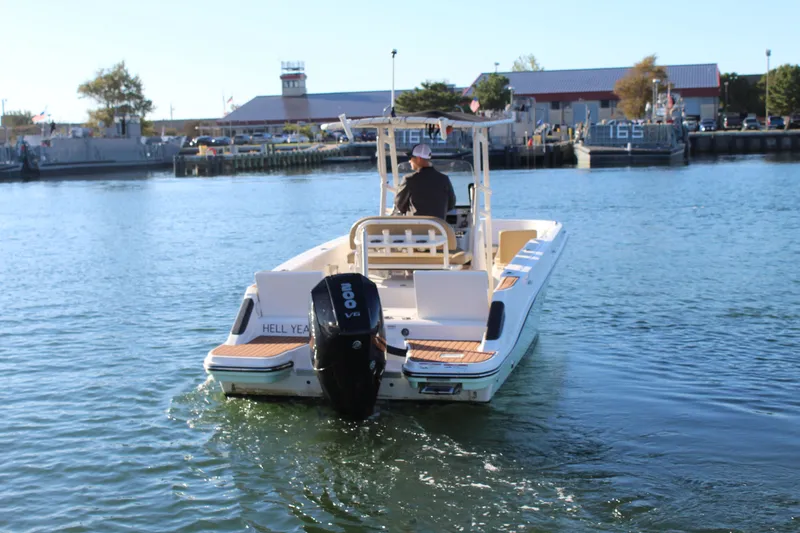 Slide: The Image of 2024 Bayliner CC22 boat cruising on a calm waterway near a marina. - 3