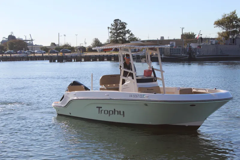Slide: The Image of 2024 Bayliner CC22 Trophy boat cruising on a calm waterway near a dock. - 6