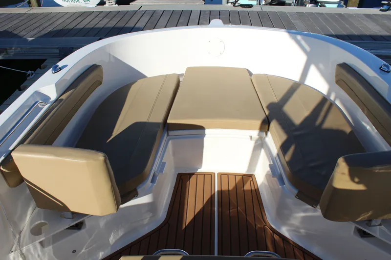 Slide: The Image of 2024 Bayliner CC22 boat interior with tan cushioned seating and wooden flooring. - 8