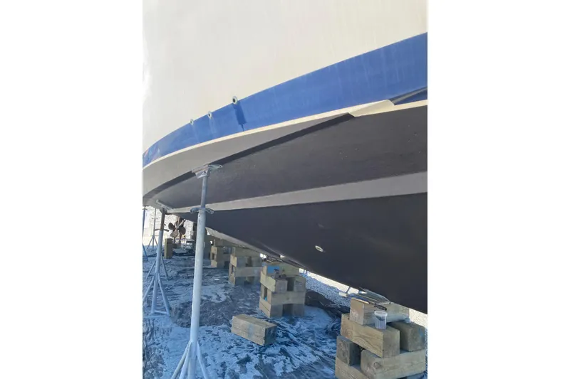 Slide: The Image of 1985 Bertram 58 Flybridge boat hull on stands, undergoing maintenance. - 2