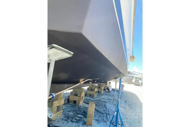 Slide: The Image of 1985 Bertram 58 Flybridge boat hull on stands, undergoing maintenance in a shipyard. - 3