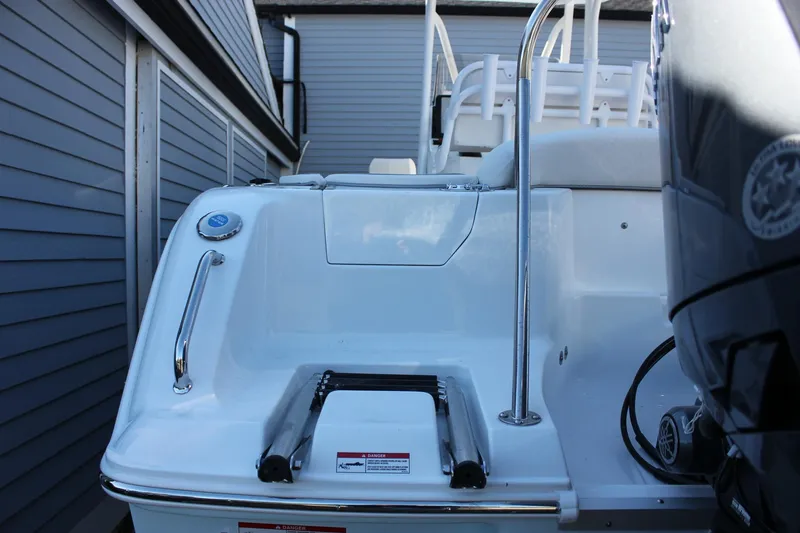 Slide: The Image of 2026 Sea Hunt Ultra 229 boat stern with ladder and railing, docked beside a building. - 13