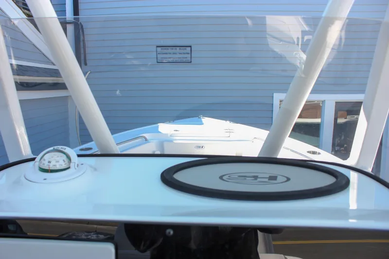 Slide: The Image of 2026 Sea Hunt Ultra 229 boat dashboard with compass and logo, docked near a building. - 15