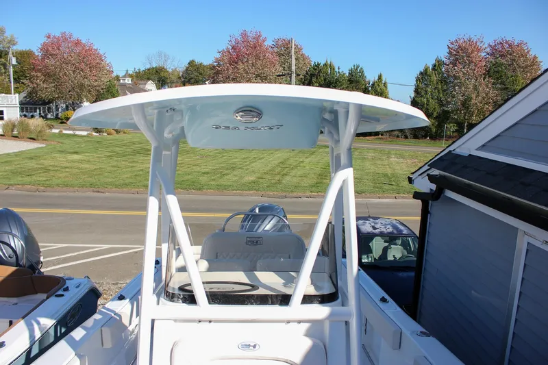 Slide: The Image of 2026 Sea Hunt Ultra 229 boat with T-top, parked near a grassy area. - 33