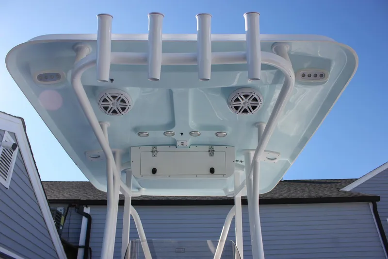 Slide: The Image of 2026 Sea Hunt Ultra 229 T-top with rod holders and speakers, under clear blue sky. - 4