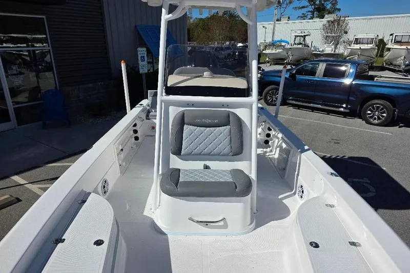 Slide: The Image of 2026 NauticStar 224 Bay boat interior with seating, parked outdoors. - 10