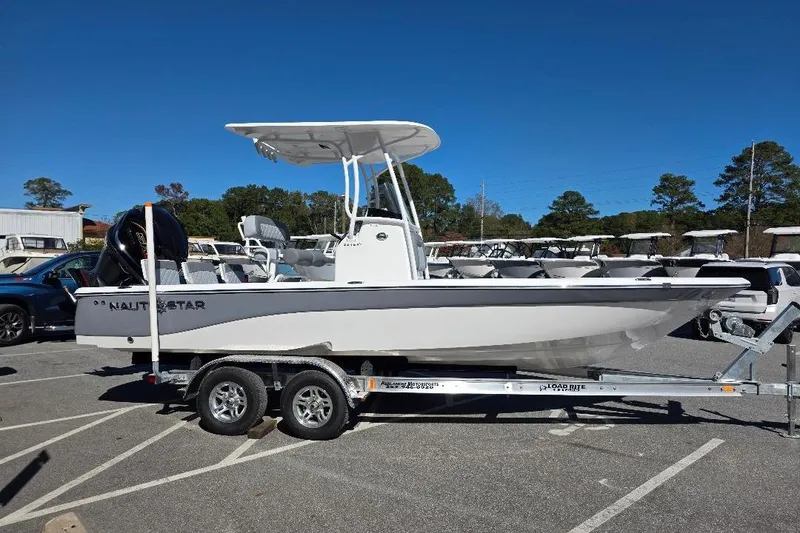 Slide: The Image of 2026 NauticStar 224 Bay boat on trailer, parked outdoors under clear blue sky. - 4