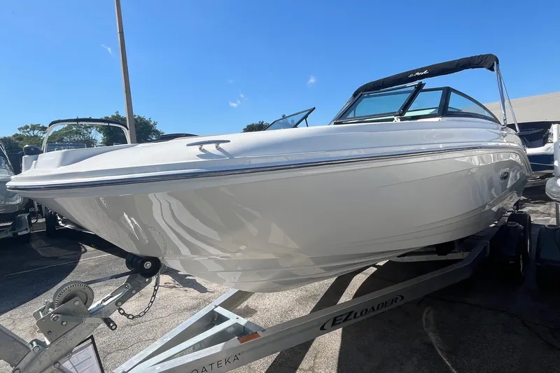 Slide: The Image of 2023 Sea Ray SPX 230 Outboard boat on trailer under clear blue sky. - 2
