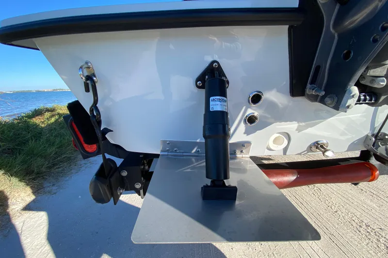 Slide: The Image of 2024 Drake Boatworks Nomad transom with trim tab and hydraulic actuator, near water. - 14