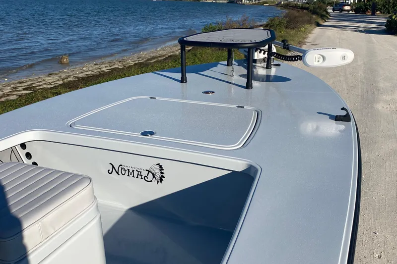 Slide: The Image of 2024 Drake Boatworks Nomad skiff by the water, showcasing sleek design and features. - 16