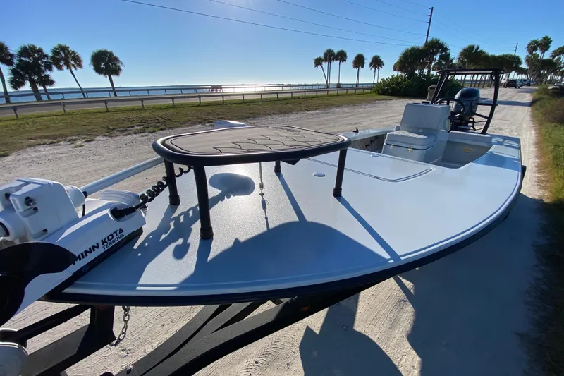 Slide: The Image of 2024 Drake Boatworks Nomad on a sunny day, featuring Minn Kota motor, near a coastal road. - 18