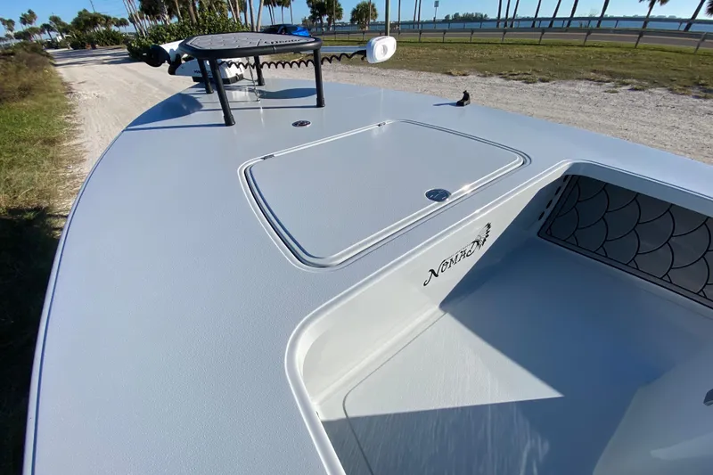 Slide: The Image of 2024 Drake Boatworks Nomad deck with storage compartment, sleek design, and scenic background. - 19