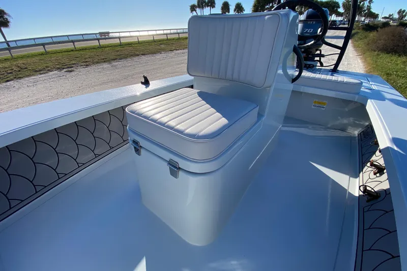 Slide: The Image of 2024 Drake Boatworks Nomad interior with cushioned seating and scenic waterfront view. - 30