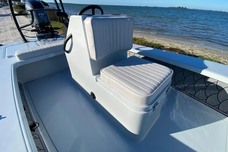 Slide: The Image of 2024 Drake Boatworks Nomad interior with cushioned seating by the water. - 31