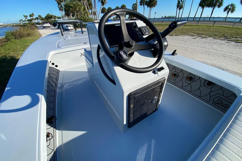 Slide: The Image of 2024 Drake Boatworks Nomad interior with steering wheel, console, and scenic waterfront view. - 37